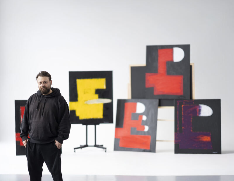 Paul Sergounine standing among his paintings